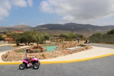 The girl rides a quad bike in a holiday park.